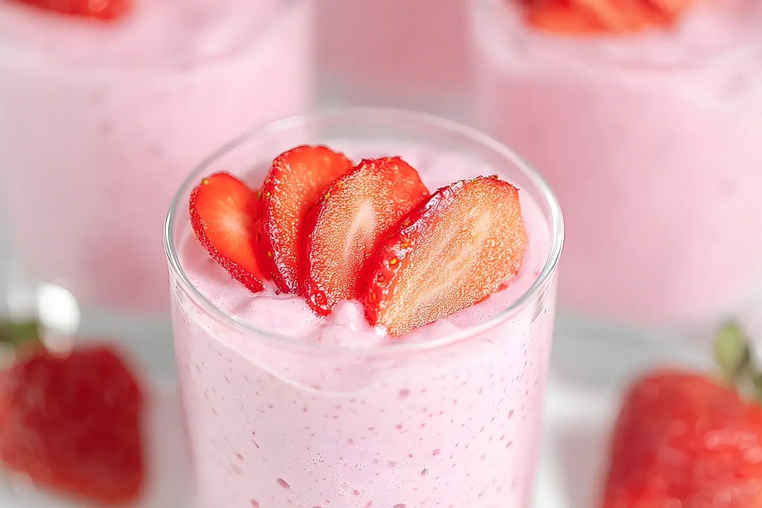 Fluffy strawberry mousse dessert topped with fresh sliced strawberries in a glass