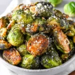 Golden roasted Brussels sprouts in a white bowl, topped with parmesan cheese for a crispy holiday side dish.