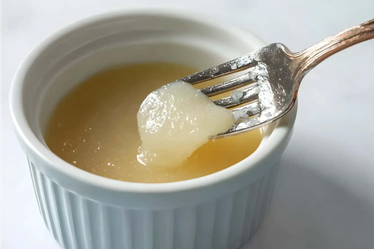 Fork lifting gelatin from a ramekin, showcasing its smooth, gel-like consistency.