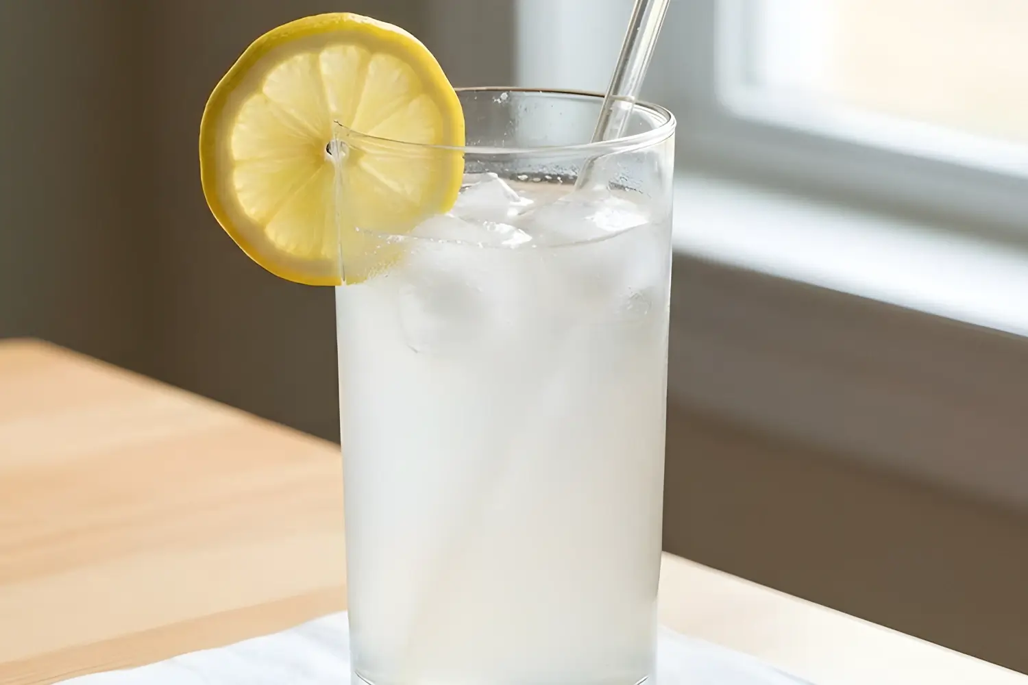 Lemon and baking soda drink served cold with ice and a lemon slice in a clear glass.